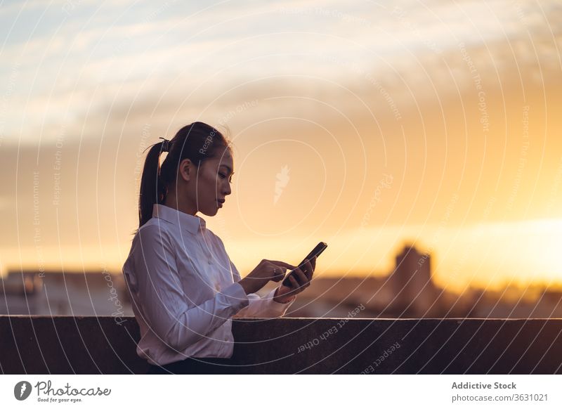 Young busy woman using smartphone on rooftop businesswoman serious focus message browsing young asian ethnic formal device gadget to go modern internet female