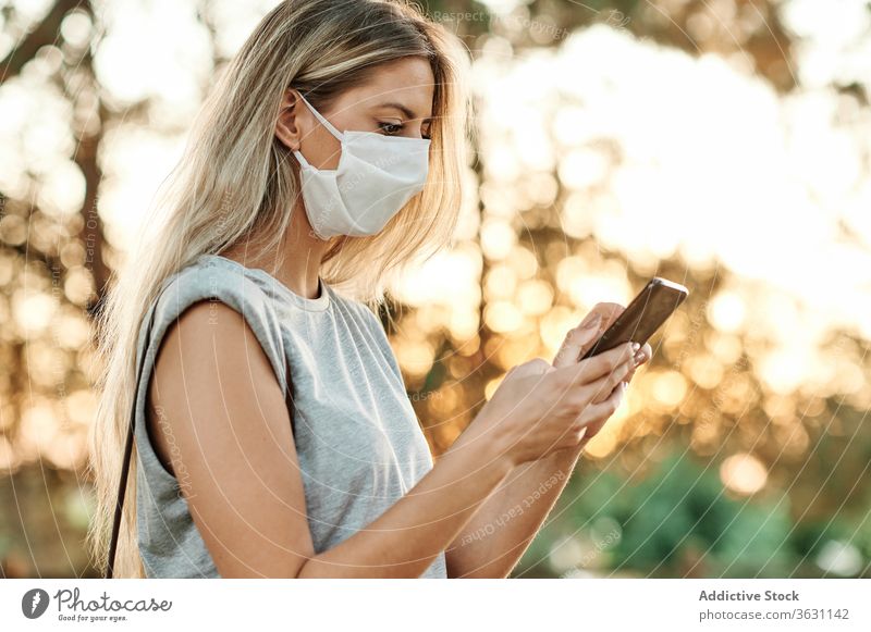 Woman with face mask on smartphone standing in park woman cheerful using happy enjoy browsing female trendy lifestyle gadget device social media online internet