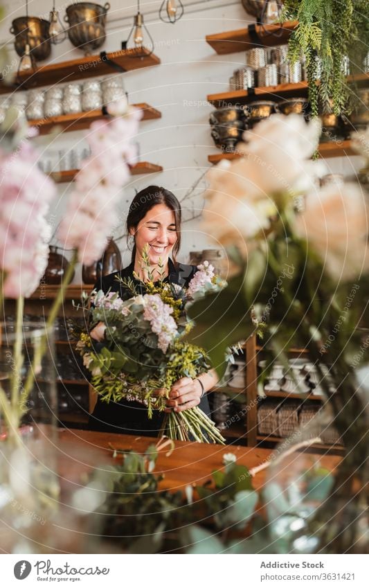 Cheerful florist with bouquet of flowers working in shop floristry woman arrange create happy bloom blossom cheerful compose designer decorative female creative