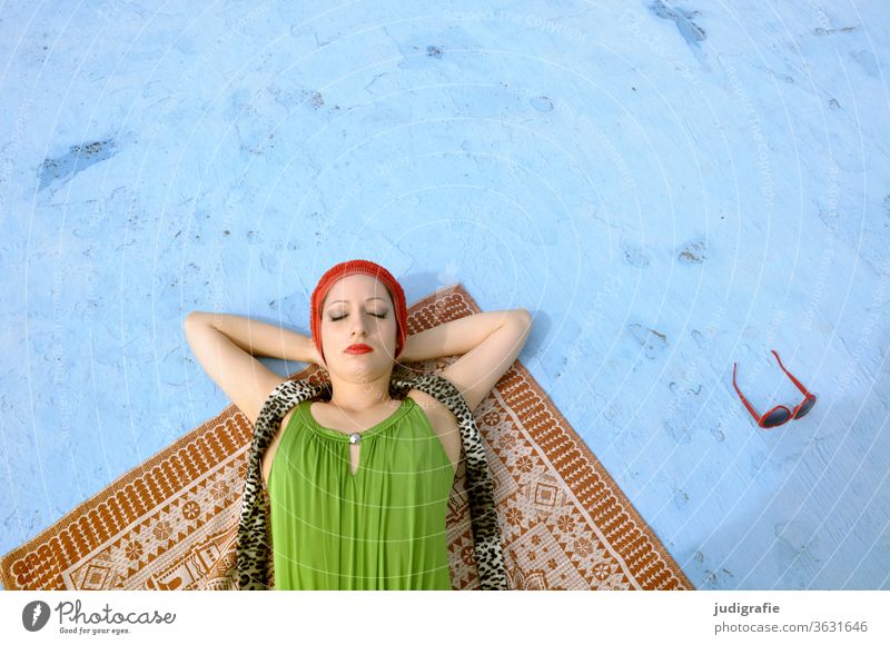 The girl with the beautiful red bathing cap and green swimsuit is sunbathing in the empty non-swimmer's pool. A summer love. Girl Woman Swimwear Bathing cap