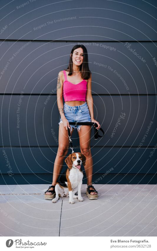 happy young woman outdoors with beagle dog. Family and lifestyle concept city urban walking casual clothing caucasian summer pet together holiday maker colorful