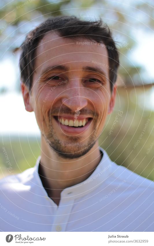 Young man in white shirt laughs Man Face of a man portrait Nature natural application motivated cheerful Facial hair Dark-haired Light (Natural Phenomenon)