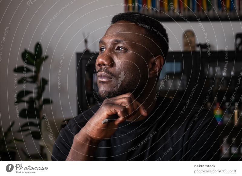 Portrait of Black Man Thinking in Living Room man 1 person hand on chin African ethnicity lifestyle 20-30 years old handsome domestic life young man male