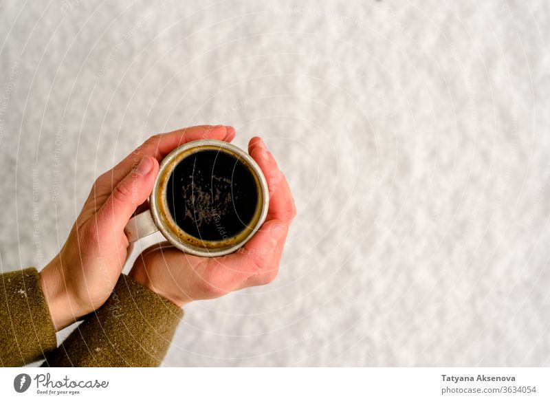 Old mug with hot coffee or tea drink on snow in winter cup cold mittens warm christmas holiday white beverage season xmas outdoor outside forest weather frozen
