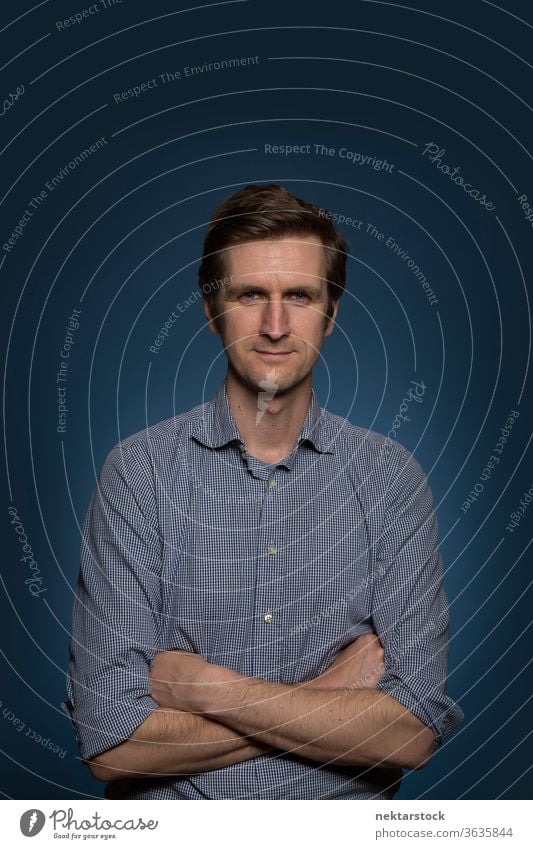 Caucasian Man Portrait with Arms Crossed 1 person arms crossed caucasian ethnicity medium shot blue background standing front facing male 30 to 40 years old