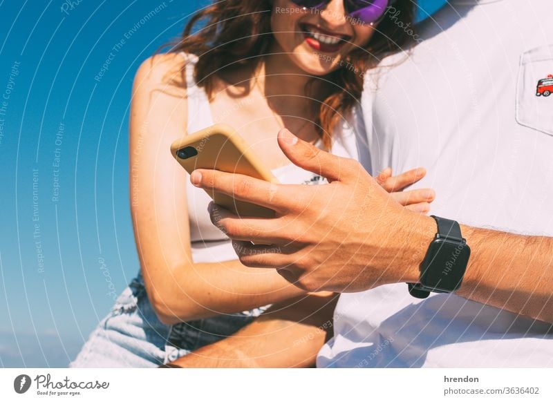 happy young couple looking at their smartphone and smiling sky female woman technology together holding lifestyle friend mobile boyfriend communication