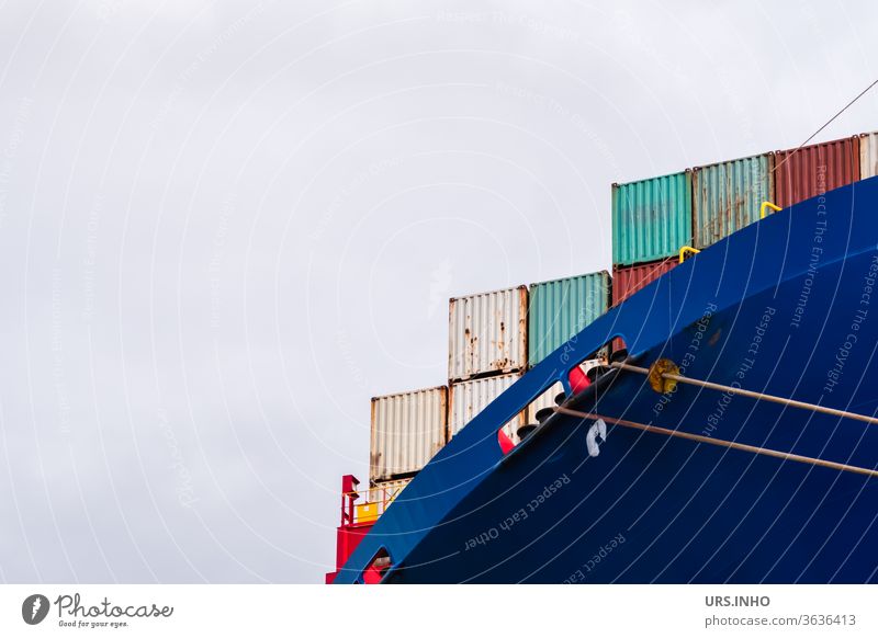 colourful containers on a huge container ship under overcast skies | detail view Container Container ship ocean liner Logistics Blue Red cloudy sky cargo