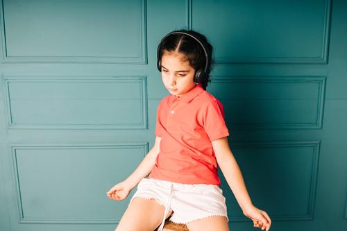 Cute girl listening music with headphones adorable alone attractive background beautiful blue carefree casual cheerful child childhood color cute dancing