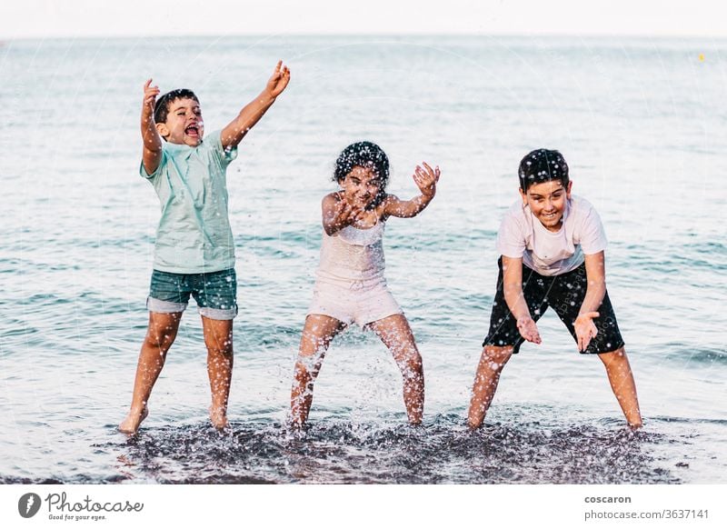 Three kids playing with the water on the beach action active beautiful blue boy bright cheerful child concept drop enjoy fresh fun funny girl happiness happy