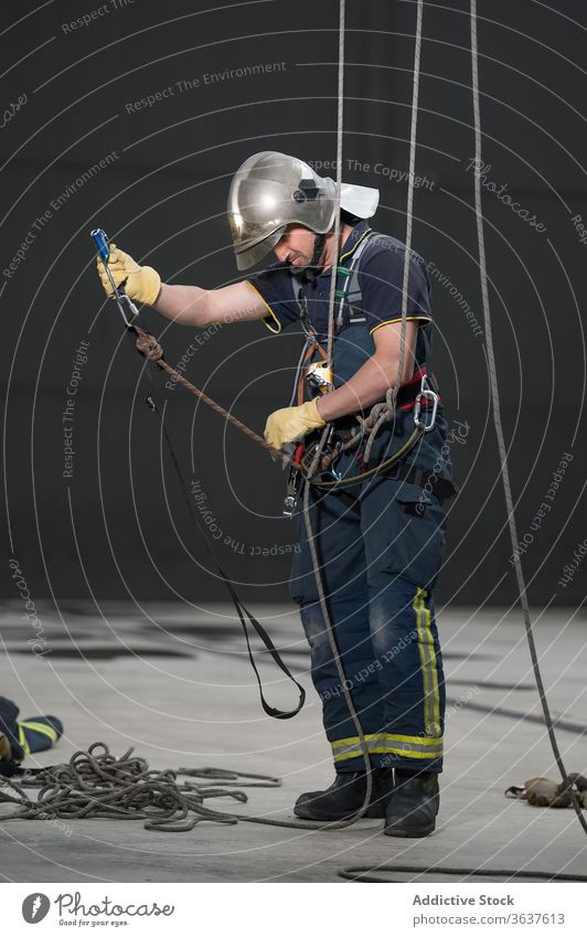 Male firefighter with ropes in training complex fireman equipment practice uniform protect adjust male brave strong rescue workout helmet hardhat physical