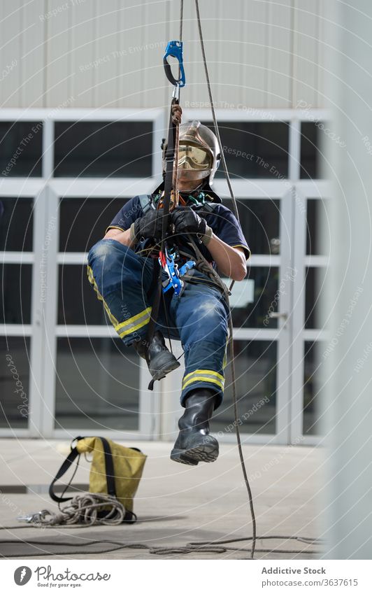 Male firefighter with ropes in training complex climb equipment fireman brave strong building practice male rescue workout uniform protect helmet hardhat