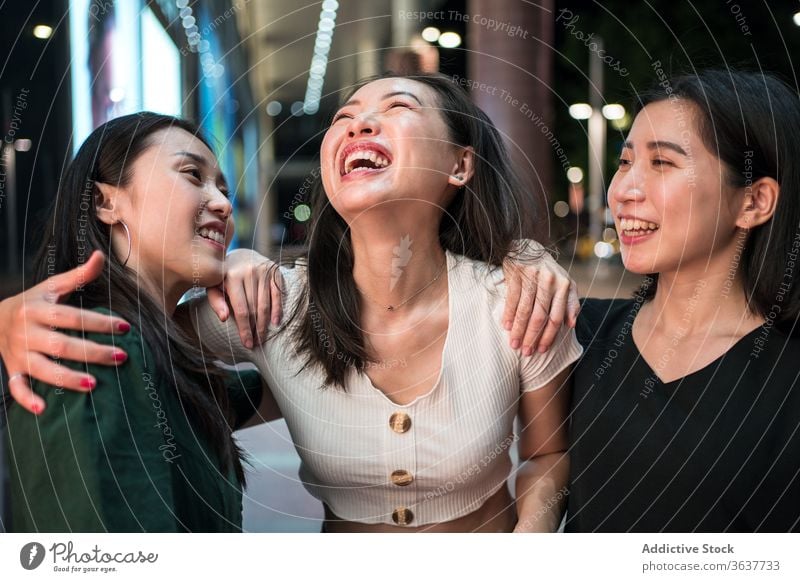 Cheerful ethnic women talking on street company laugh together girlfriend stroll city night cheerful humor friendship asian walk relationship smile joy urban
