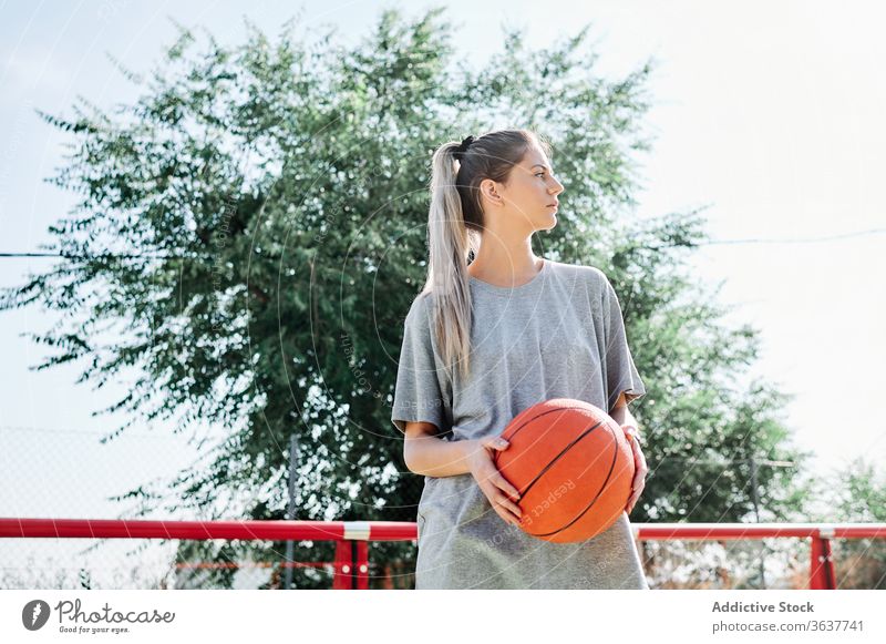Confident basketball player standing on playground woman confident sport court competitive serious young sportswoman athlete sportswear training activity game