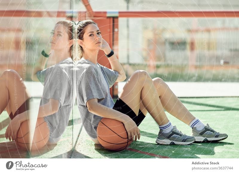 Tired sportswoman with basketball ball resting on court relax tired sit young athlete sportswear training activity game player workout exercise break active