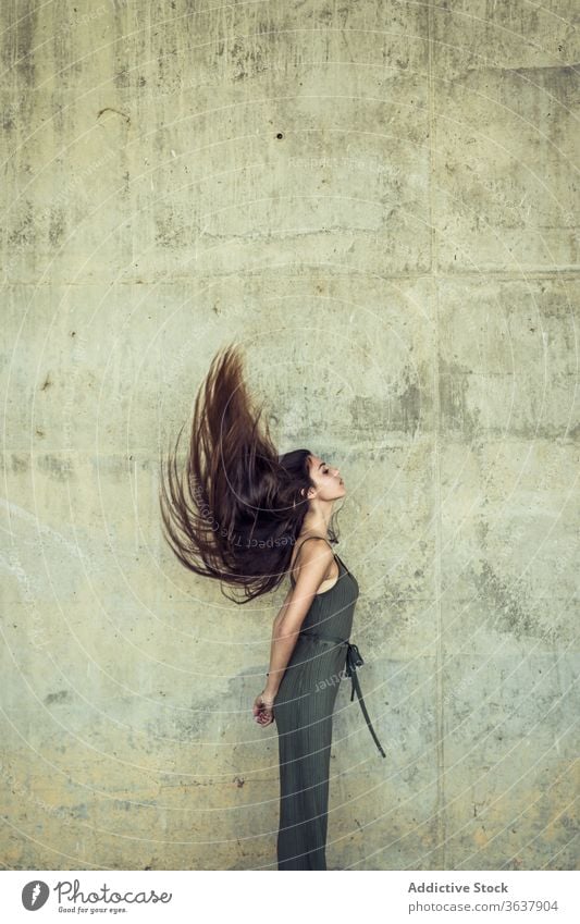 Young woman with flying hair grace beauty long hair city charming tender urban harmony female slim stone wall shabby weathered facade exterior stand sensual