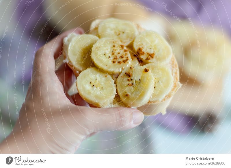 Shallow depth of field of hand holding a toast topped with banana slices and cinnamon powder vegan natural home homemade delicious vegetarian diet lifestyle
