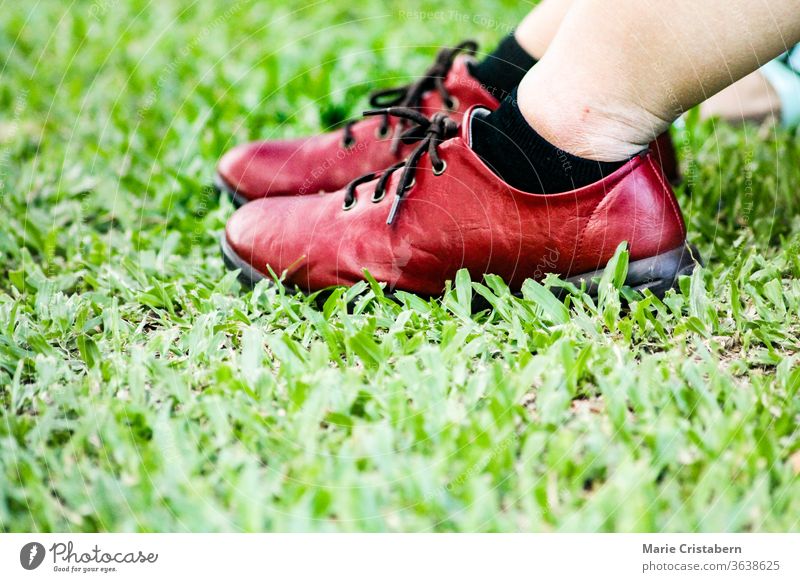 pair of red leather shoes against the green grass in the park alone background color concept copy space covid-19 pandemic elegance fashion fashionable feet