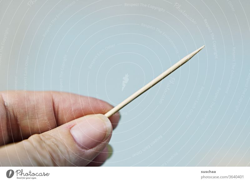 pointed toothpick, held by one hand Toothpick Long peak dental care by hand Fingers stop Neutral background wood