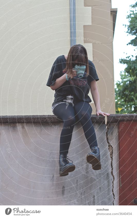 teenage girl sitting on a wall taking pictures of her feet Legs foot Footwear Boots Cool Sit Youth (Young adults) Wall (barrier) crack in the wall Exterior shot