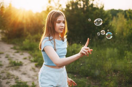 Cute girl with a beautiful smile catches soap bubbles on the background of a beautiful sunset. little blowing cute kid fun child childhood summer healthy pretty