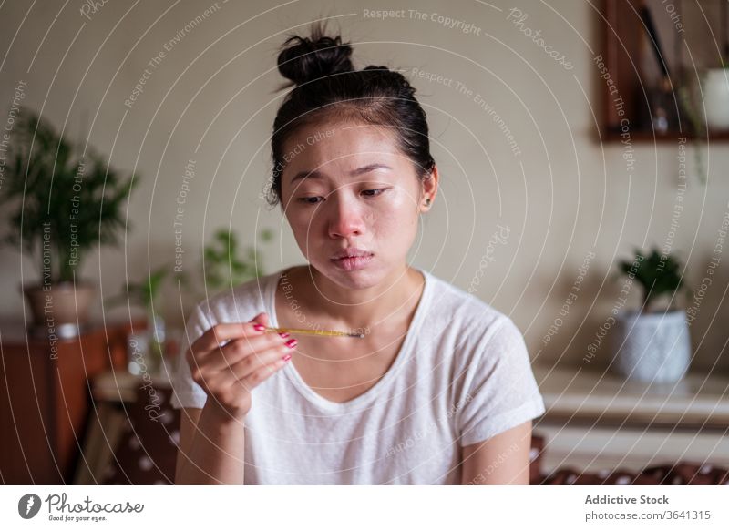 Sick Asian woman measuring temperature sick measure ill have cold flu thermometer home unwell female asian ethnic running nose handkerchief paper bed rest