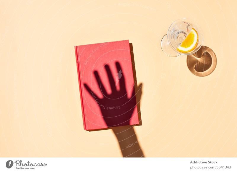 Hand of crop person and notebook on pink background notepad diary studio glass water slice shadow refreshment orange natural bright table drink creative summer