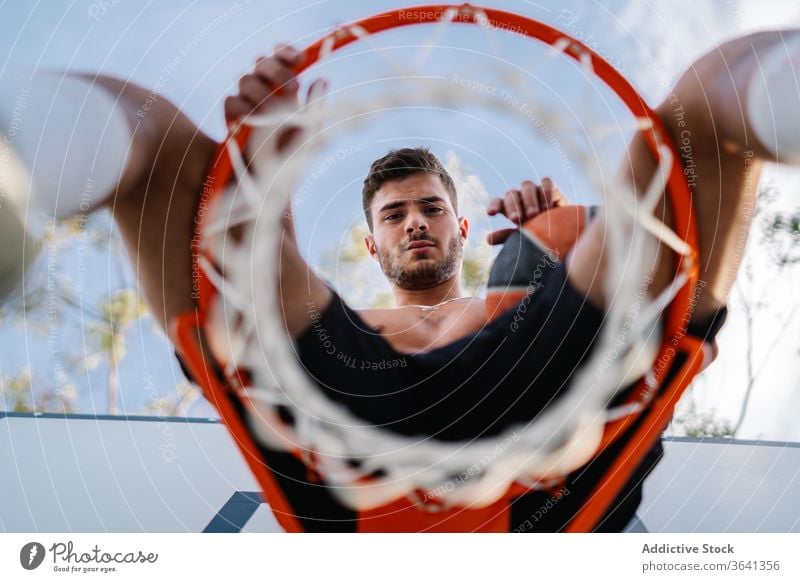 Basketball player sitting on hoop on playground basketball man sportsman training game healthy male handsome professional activity exercise sportswear athlete