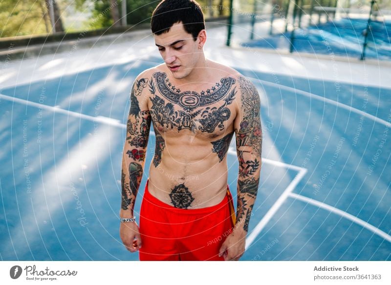 Confident male athlete on sports ground sportsman playground workout shirtless confident tattoo naked torso summer training strong body muscular fit modern