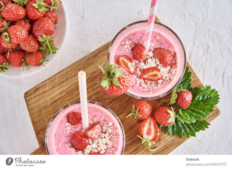 Strawberry milk shake in glass with straw and fresh berries on a white background strawberry juice smoothie cocktail cream beverage blended breakfast drink food