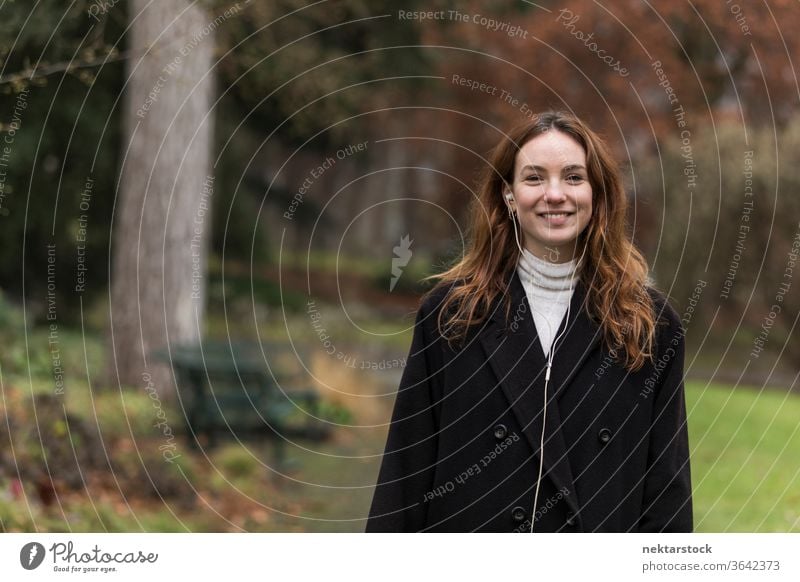 Young Woman with Toothy Smile Posing in Autumnal Park caucasian ethnicity woman female earphones audio music listening brown hair real life model real person