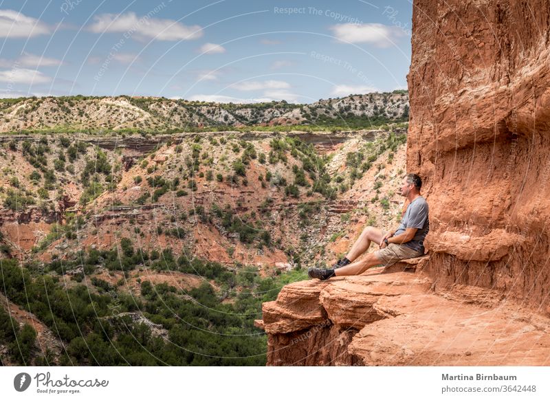 Man sitting on the edge of the Lighthouse Rock, Palo Duro Canyin State Park, Texas man 50-54 hiking hike active lighthouse rock canyon desert dramatic clouds