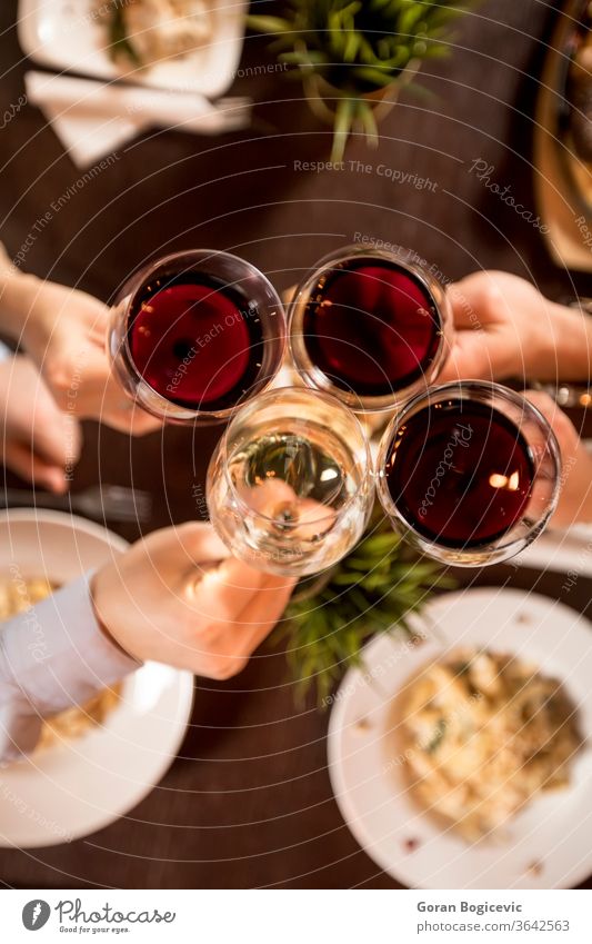 Four hands with red wine toasting over served table with food restaurant party holding view top cheers people drink friends lifestyle friendship beverage dinner