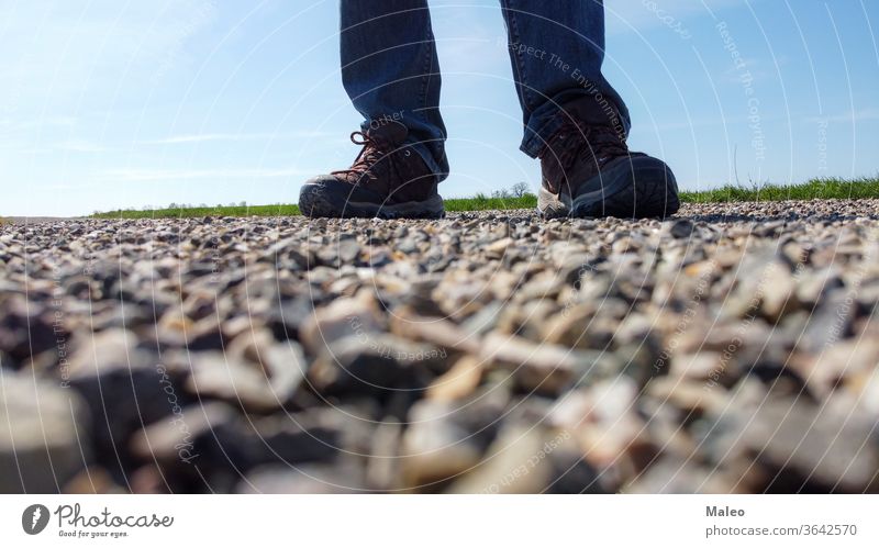 Legs of a man in sneakers stand on a gravel road day top view cobbled feet leg outdoor people rock shoes sidewalk standing stone texture travel arriving beach