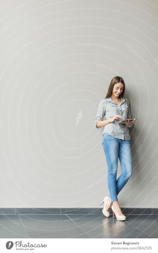 Woman with tablet by the wall adult casual caucasian communication computer contemporary copyspace digital display grey female handsome internet woman cute