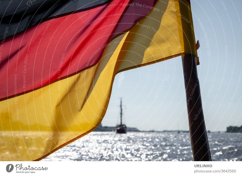 the flag of Germany flies in the wind of the sea German flag Black Red Gold German Flag Politics and state Patriotism Ocean Exterior shot Deserted Ensign