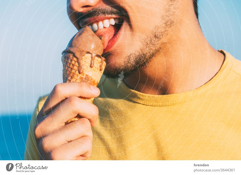 young man in yellow licks his chocolate ice cream blue close-up colorful cone cool creamy eat eating enjoy enjoying Enjoyment freedom fun funny gelato happiness