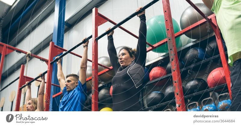 Athletes ready to do pull ups in the box group rack cross fit hanging bar wod workout of the day exercise banner panorama panoramic web fitness sport chin ups