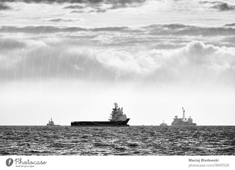 Black and white picture of ships silhouettes on the horizon at sunset. sea ocean transport travel water journey black and white sky vessel boat cloudscape