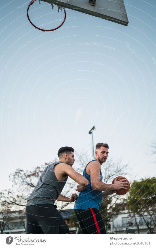 Two young friends playing basketball. game youth sport court male team together active action playground exercise men friendship jump happy athlete fitness