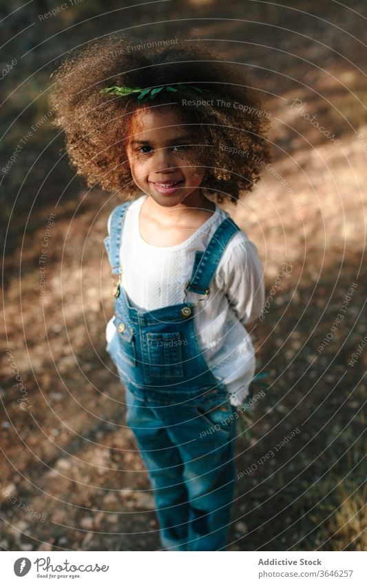 Little mulatto girl on blurred nature background black child portrait calm adorable summer style outfit curly hair cute sunlight sunny stand lifestyle kid
