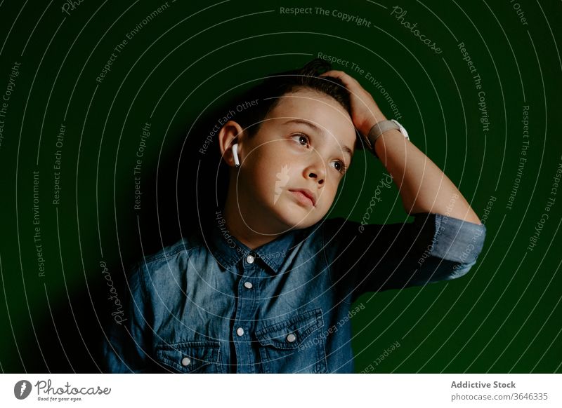 Schoolboy looking away posing in colorful wall using earbuds confident cool achieve unemotional friendly style lifestyle kid preteen portrait show optimist