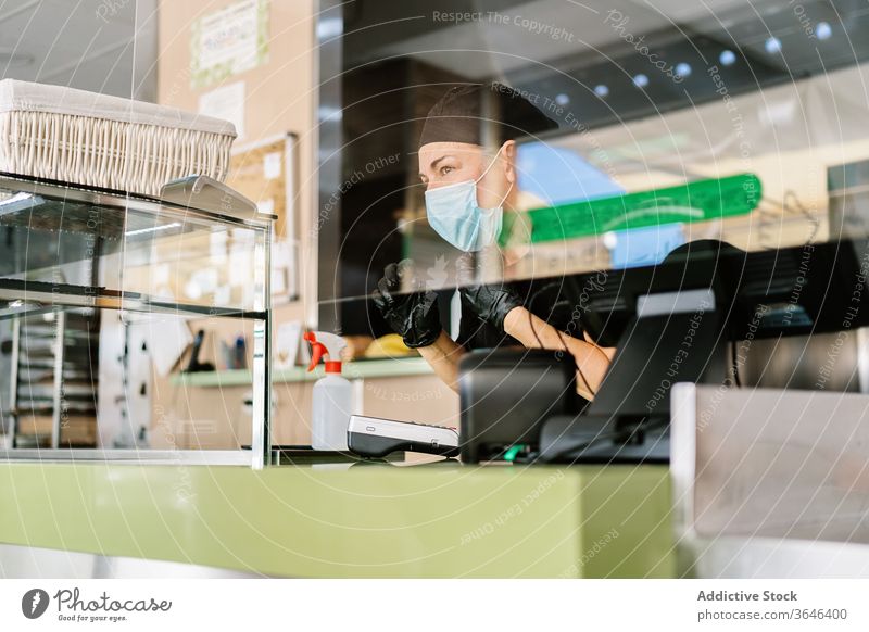 Concentrated female cashier in face mask working with cash till woman respirator counter cafe coronavirus concentrate positive coworker prevention