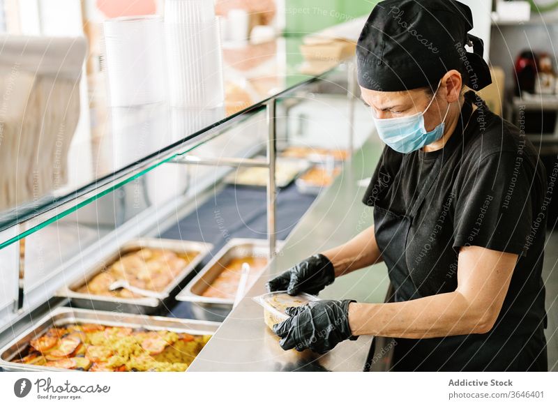 Cafe worker packing food in plastic container for takeaway waitress respirator coronavirus tasty busy glove concentrate woman cuisine service yummy delicious