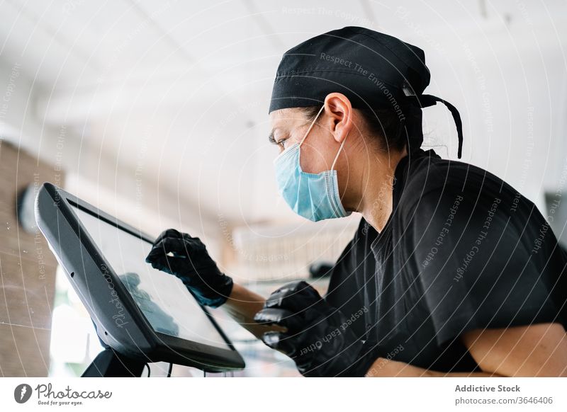 Focused female cashier in face mask working with cash till woman respirator counter cafe serious focus coronavirus at work duty concentrate small business