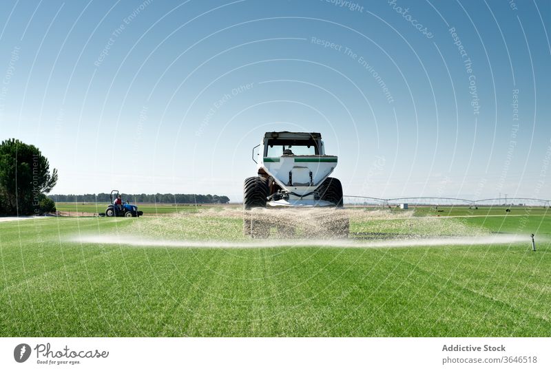 Industrial tractor watering agricultural field agriculture machine green grass countryside nature rural meadow industrial summer farm vehicle landscape daytime