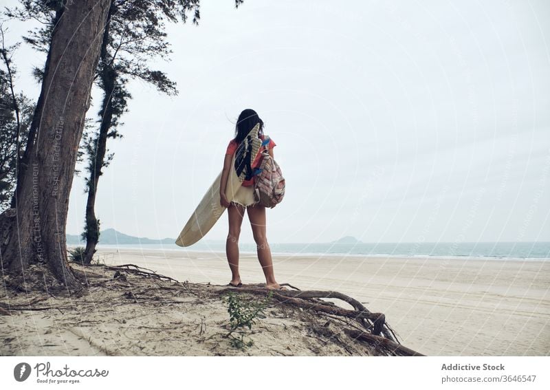 Anonymous female surfer walking on beach with surfboard woman sandy carry content sea casual seaside carefree activity young sporty tree tranquil lifestyle