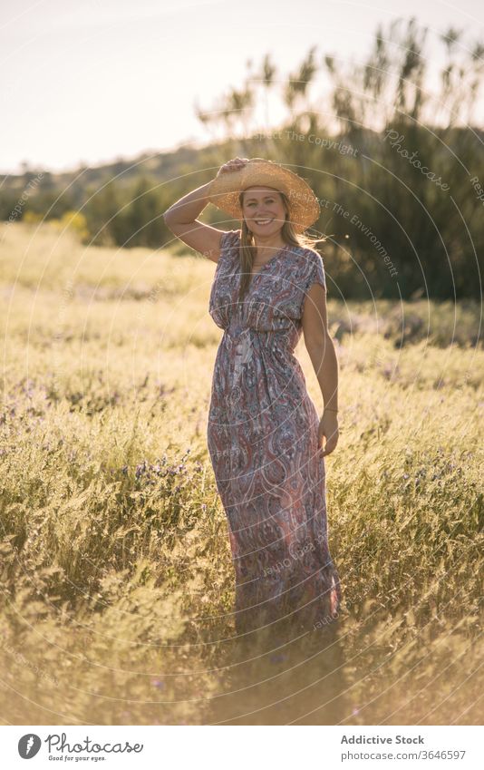 Charming woman in green field summer enjoy dress meadow sunny straw hat smile nature female cheerful vacation trendy stand freedom weekend daytime carefree rest