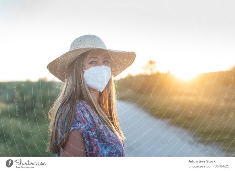 Charming woman in medical mask in countryside coronavirus epidemic enjoy sunset rural charming summer female sundown road carefree nature evening covid 19