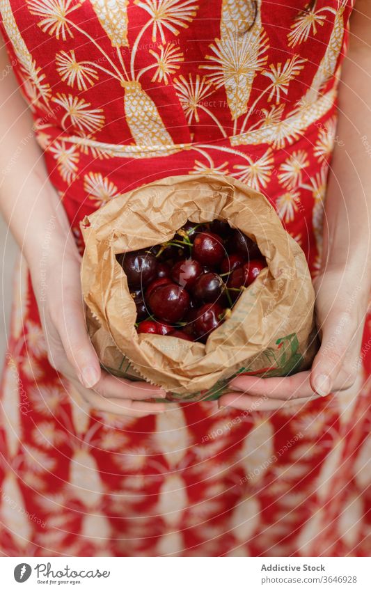 Crop woman with fresh cherry in bag ripe paper bag organic natural grocery summer tasty female dress food product raw package vegan shopper nature delicious