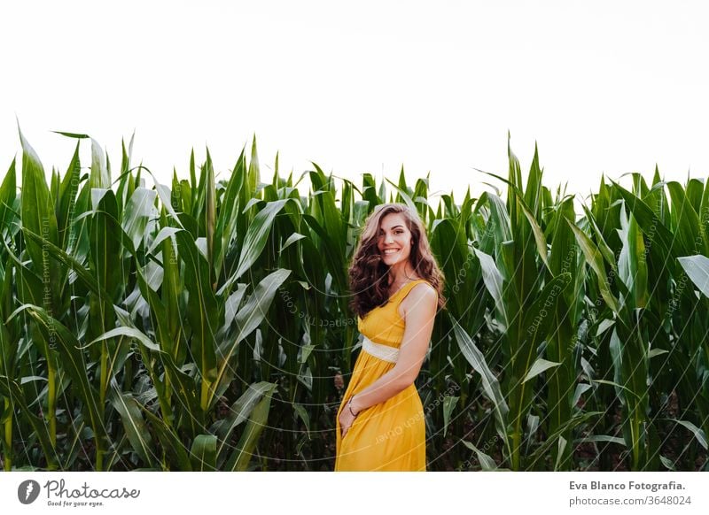 portrait of young beautiful woman wearing a yellow dress standing in a green corn field. Summertime and lifestyle 1 beauty carefree casual caucasian cheerful